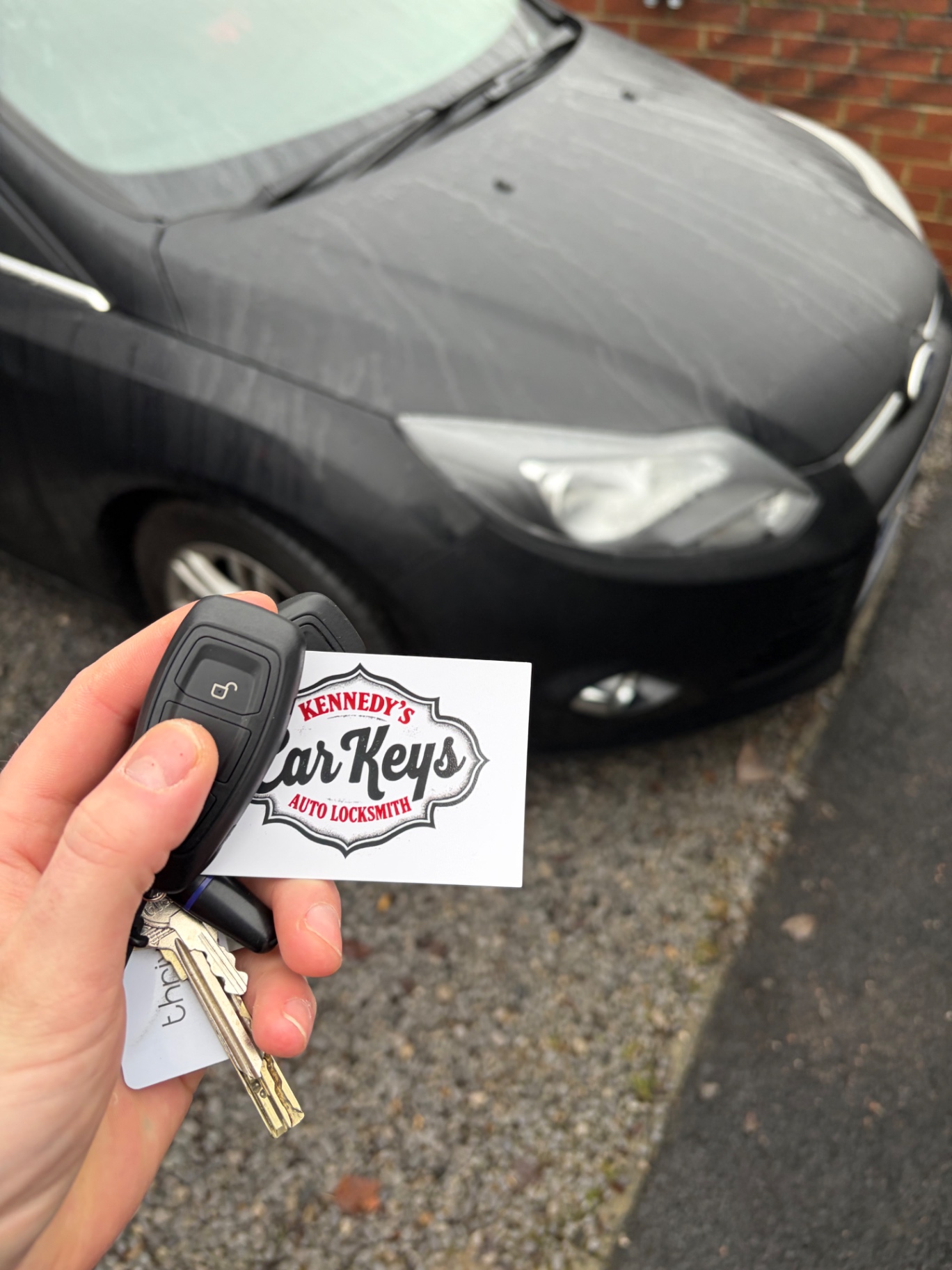 Kennedy's Car Keys business card held in front of a customer's Ford Focus